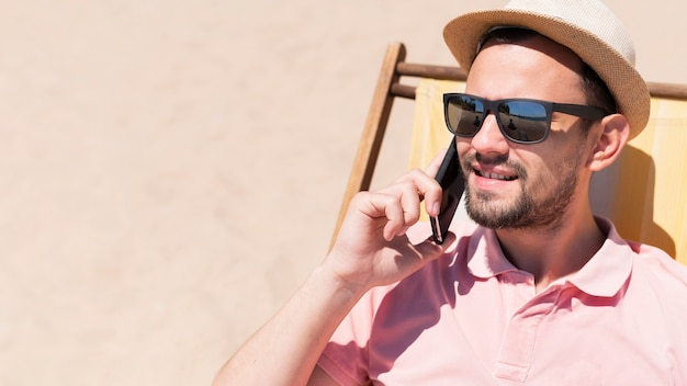 Man praten over smartphone in strandstoel