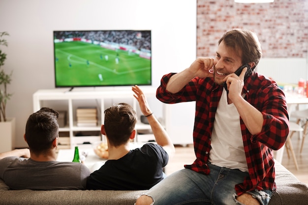 Man praten via de telefoon tijdens voetbalwedstrijd