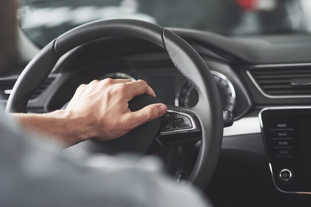Man's grote handen op een stuur tijdens het besturen van een auto.