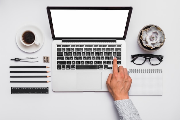 Man&#39;s hand op laptop toetsenbord over bureau met geregeld kantoorbenodigdheden