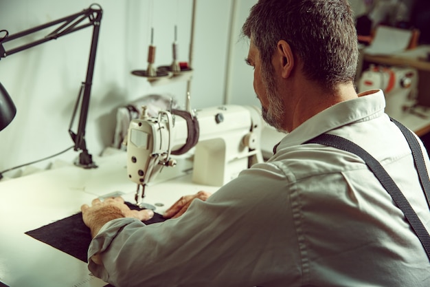 Man's handen achter het naaien. leerwerkplaats. textiel vintage industrieel. de man in vrouwelijk beroep. gendergelijkheid concept