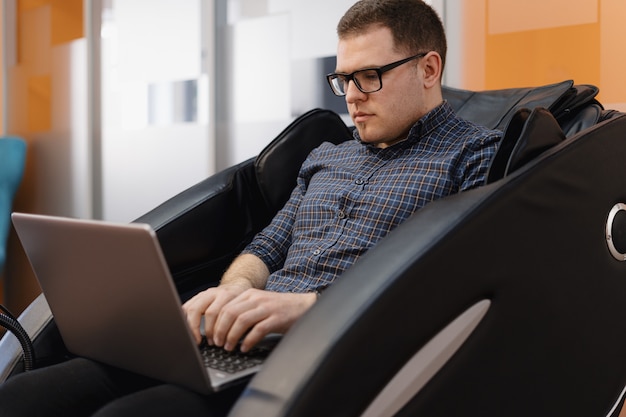 Man schrijven code zittend in fauteuil in het kantoor