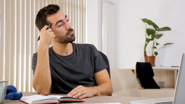 Man schrijven op notebook aan zijn bureau. Gedachten op papier zetten.