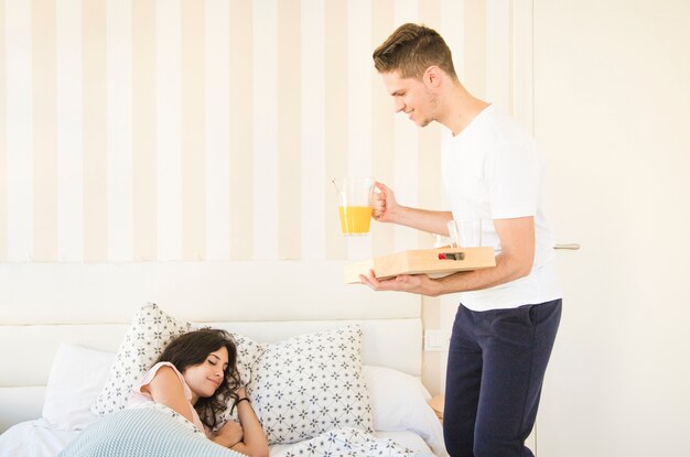 Man serveert ontbijt op bed voor de vrouw