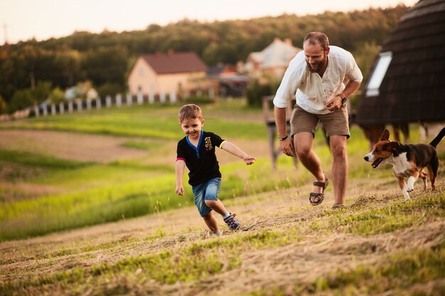 Man speelt met zijn zoon en een hond op het veld