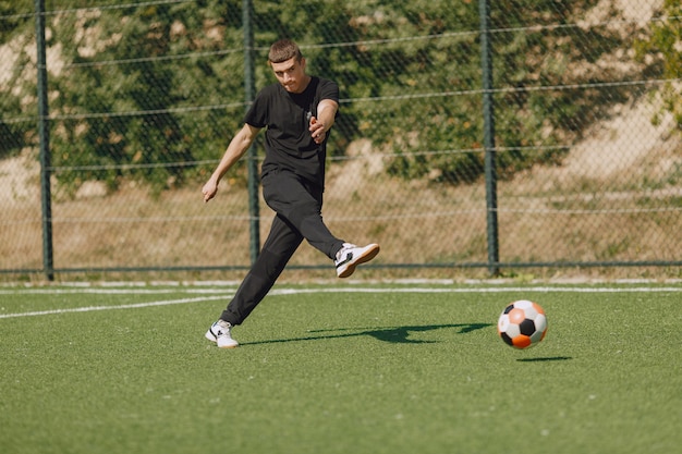 Man speelt socerl in het park. Toernooi op mini-footbal. Kerel in zwarte sportpakken.