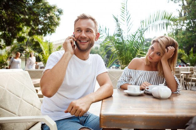 Man spreken over de telefoon terwijl zijn vriendin wordt verveeld.