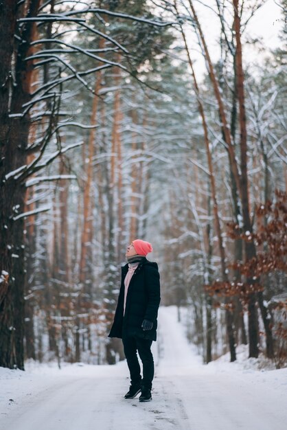 Man staat op de weg midden in het bos, omringd door sneeuw