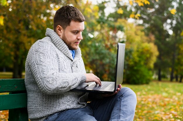 Man surfen op laptop zittend op een bankje