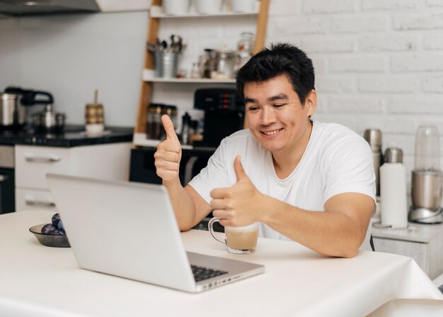 Man thuis tijdens de pandemie duimen opdagen tijdens een videogesprek op laptop