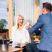Gratis foto man toont een verlovingsring met zijn verbaasde vriendin in een restaurant