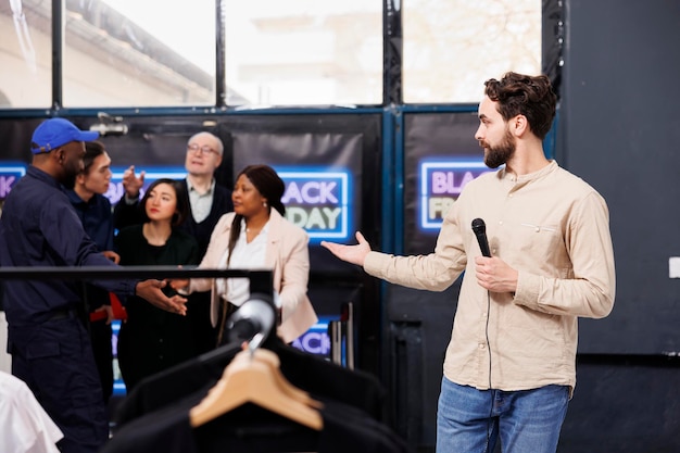 Man tv-verslaggever die bij de ingang van het winkelcentrum staat en nieuws over black friday presenteert. bewaker van kledingwinkel die de deur opent voor enthousiaste mensen die wachten op kortingen en seizoensverkopen