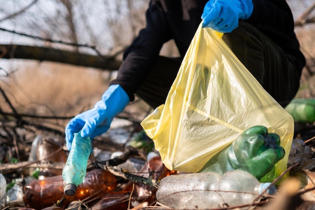 Man verzamelt verspreide plastic flessen van de grond