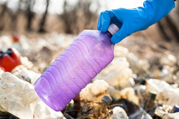 Gratis foto man verzamelt verspreide plastic flessen van de grond