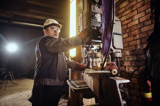 Man werkt met gigantische boor in drukke metaalfabriek.