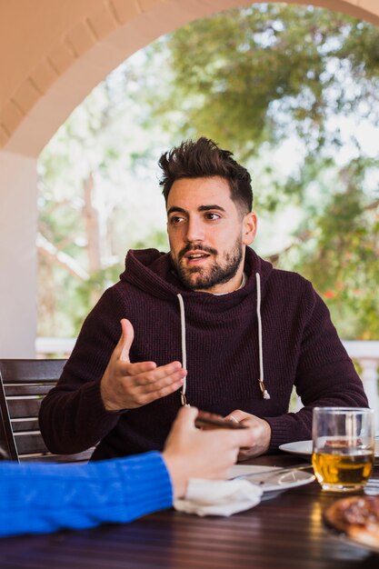 Gratis foto man zit aan tafel buiten praten met persoon