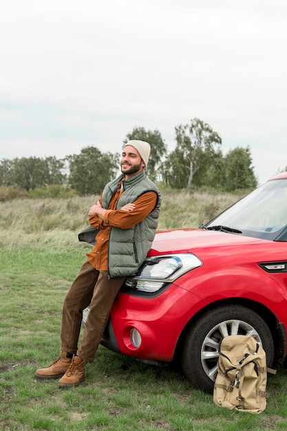 Man zit op de motorkap van de auto in de natuur