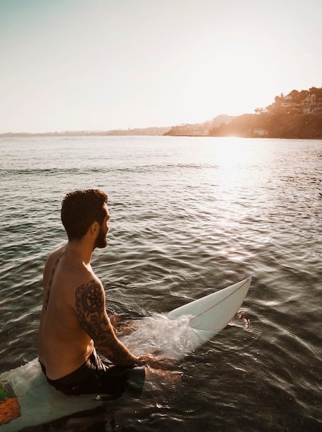 Man zit op surfplank in water