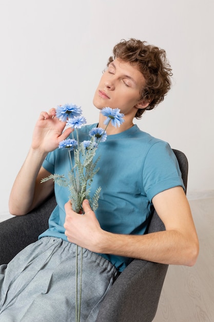 Man zittend in een stoel en bloemen te houden