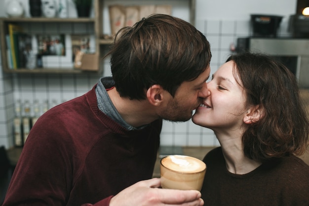 Man zoenen zijn vriendin terwijl u een kopje koffie