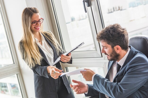 Manager die document aan haar vrouwelijke secretaresse op het kantoor geeft