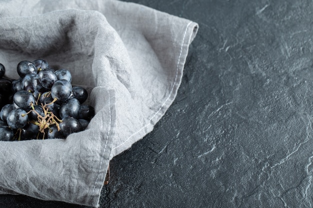 Mand van druiven met grijs tafelkleed op marmer.
