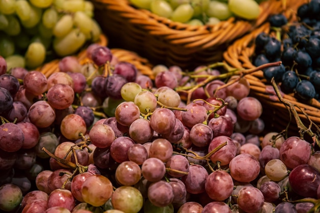Manden met verschillende soorten druiven op een supermarktvitrine