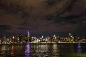 Gratis foto manhattan bij nacht die van veraf met rivierbezinning is ontsproten