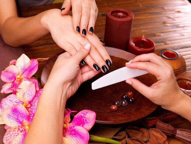 Manicure meester maakt manicure op handen van de vrouw - Spa behandeling concept