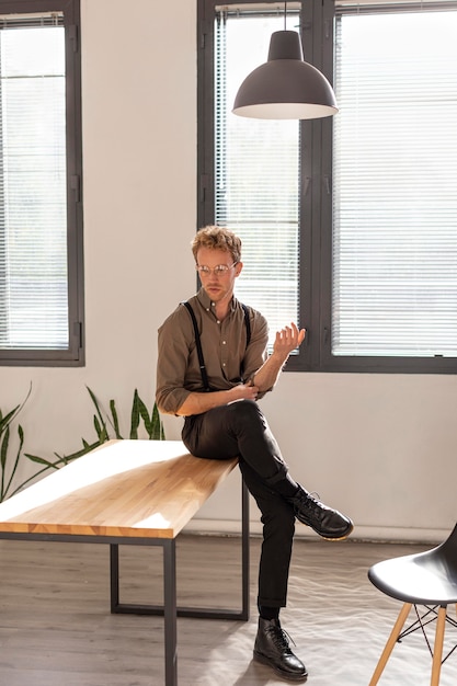 Mannelijk model met krullend haar zittend op de tafel afstandsschot