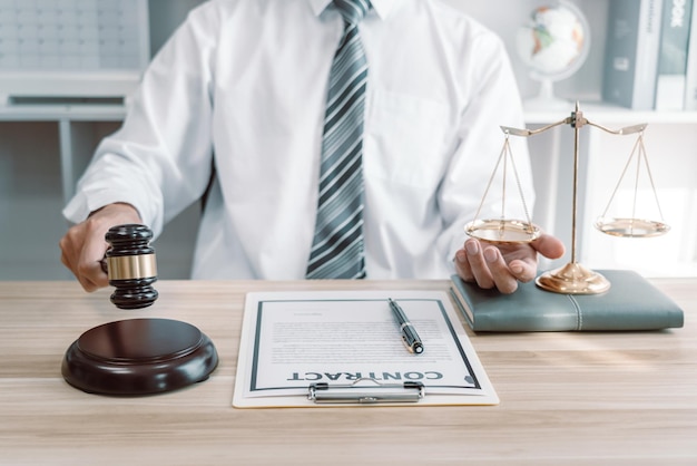 Mannelijke advocaat die werkt met papieren procesdocumenten van het landgoedrechtszaak, wetboeken en houten hamer op tafelkantoor.