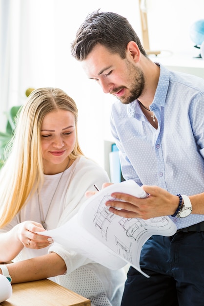 Mannelijke architect die blauwdruk toont aan zijn vrouwelijke collega