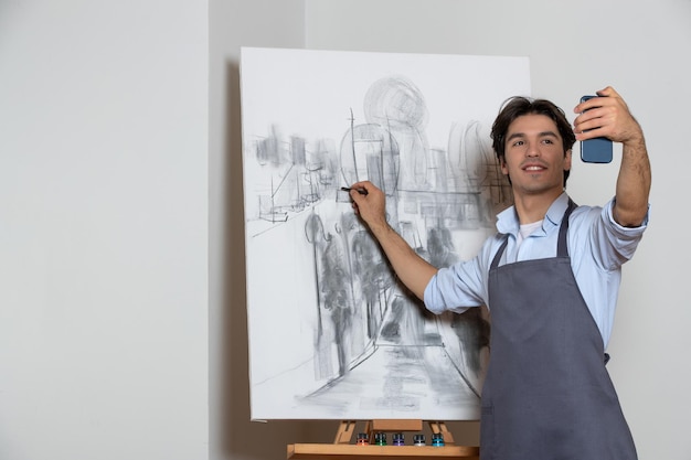 Mannelijke artiest die selfie neemt met zijn zwart-wit schilderij witte achtergrond tekening kunst