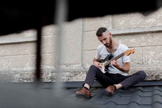 Mannelijke artiest op het dak elektrische gitaar spelen