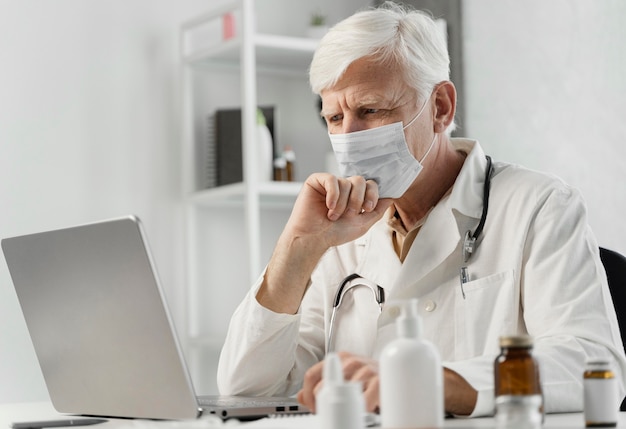 Mannelijke arts aan zijn bureau met wat medicijnen