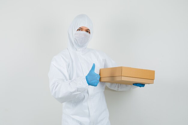 Mannelijke arts in beschermend pak, handschoenen, masker met kartonnen doos