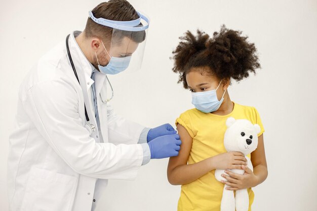 Mannelijke arts plakt een pleister op de schouder van een meisje na een vaccinatie
