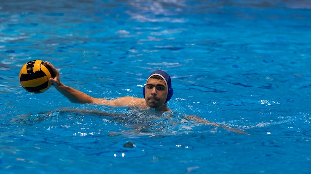 Gratis foto mannelijke atleet die waterpolo speelt in binnenzwembad