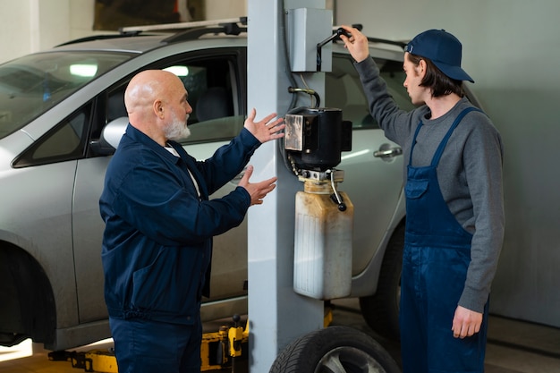 Gratis foto mannelijke automonteur die werkt in de autoreparatiewerkplaats