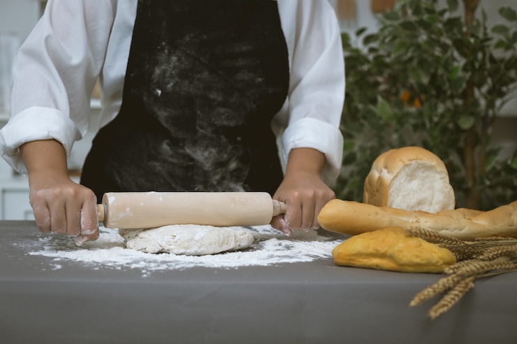 Gratis Foto mannelijke bakker bereidt brood met bloem voor