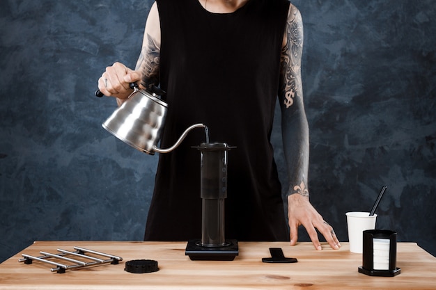 Mannelijke barista koffie brouwen. Alternatieve methode aeropress.