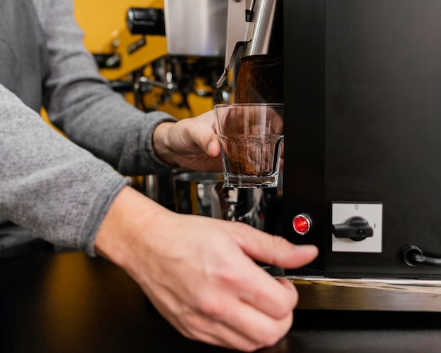 Mannelijke barista koffie malen in de coffeeshop