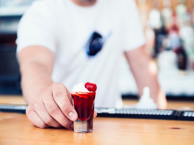 Gratis foto mannelijke barman die kleurrijk rood schot dient