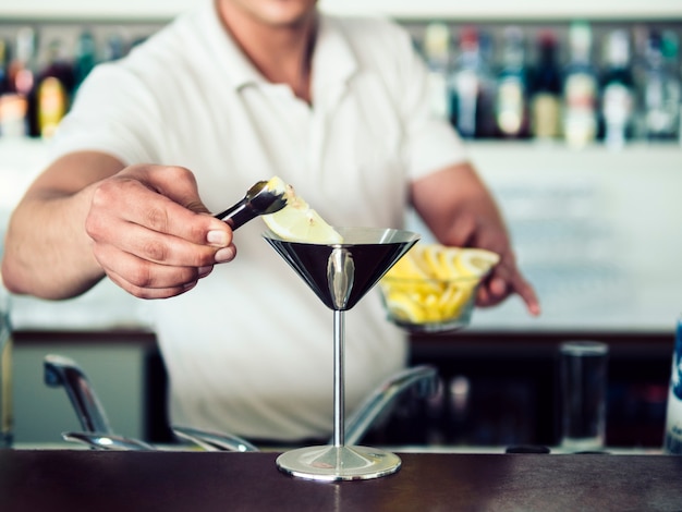 Mannelijke barman dienende cocktail in roestvrij martini-glas