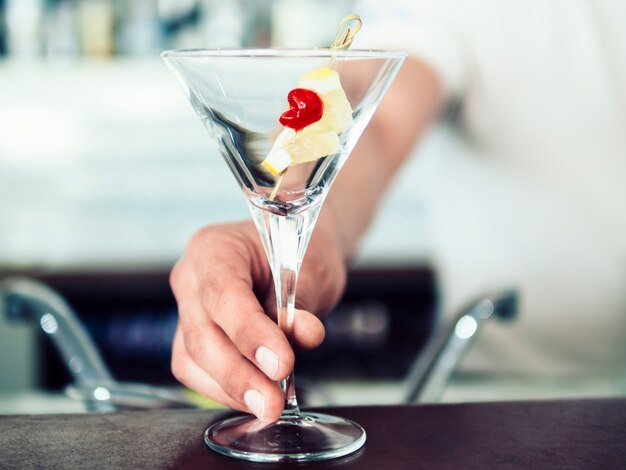 Mannelijke barman dienende cocktail met fruit
