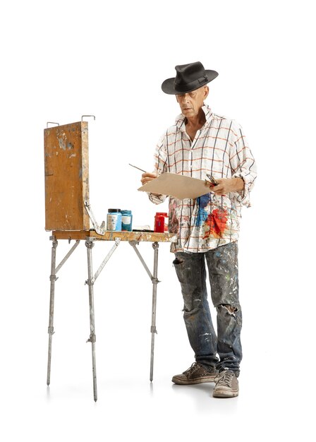 Mannelijke blanke kunstenaar, schilder op het werk geïsoleerd op witte studio