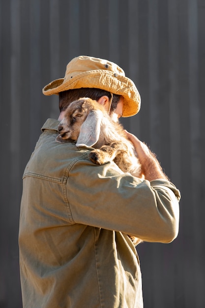 Gratis foto mannelijke boer hoedt zijn geiten op de boerderij