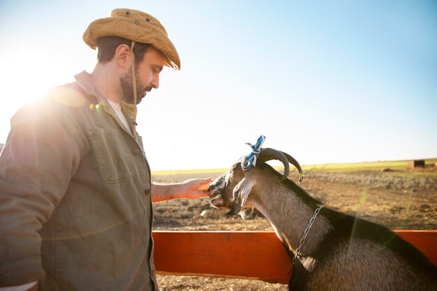 Mannelijke boer hoedt zijn geiten op de boerderij