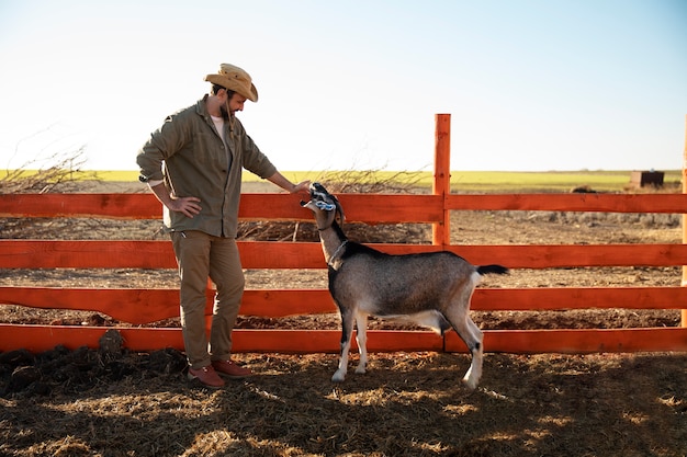 Gratis foto mannelijke boer hoedt zijn geiten op de boerderij