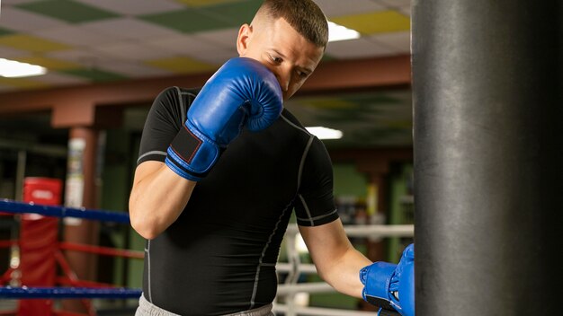 Mannelijke bokser met handschoenen die aan de ring trainen